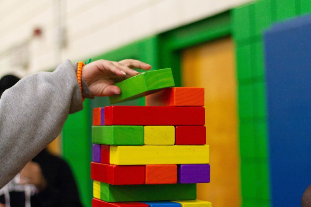 Un enfant qui construit un tour avec des blocs colorés en bois/A child building a tower with colourful wooden blocks