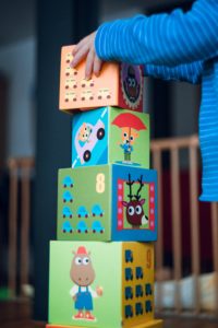 Un enfant construit un tour avec des blocs colorés. A child is building a tower with colourful blocks.